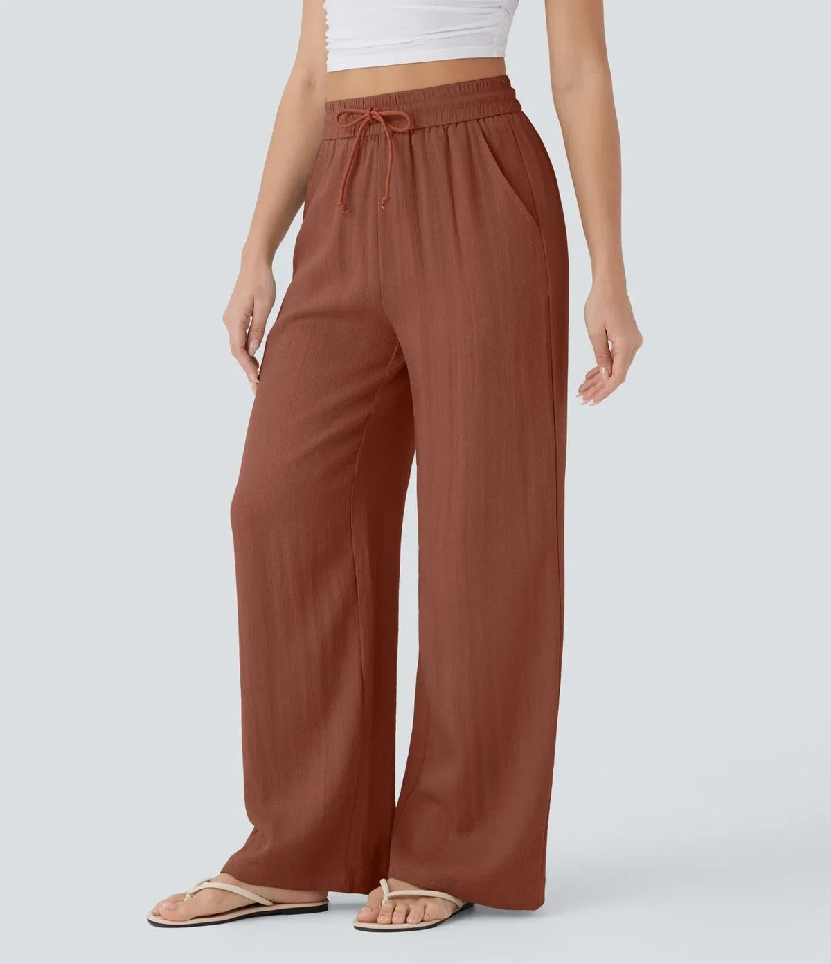 Rust brown wide-leg trousers with elastic waist and drawstring, full-length wide legs.