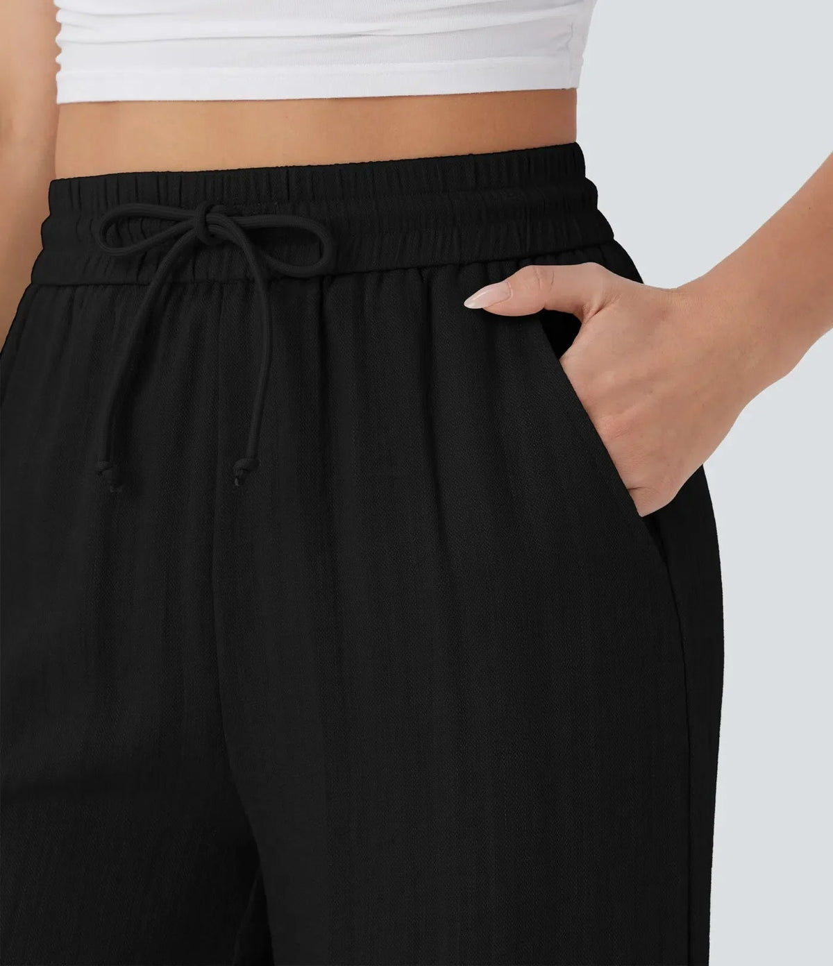 Black wide-leg trousers: elastic waistband with drawstring bow detail.
