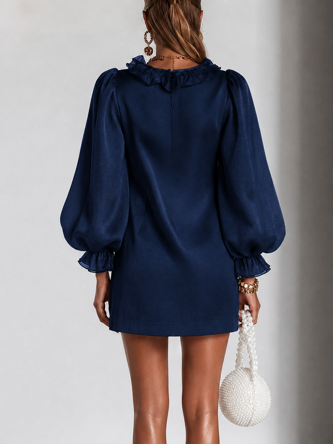 Navy satin mini dress from back view with gathered puff sleeves and pleat detail