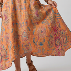 Orange printed midi dress close-up with draped hem and cuffed sleeve