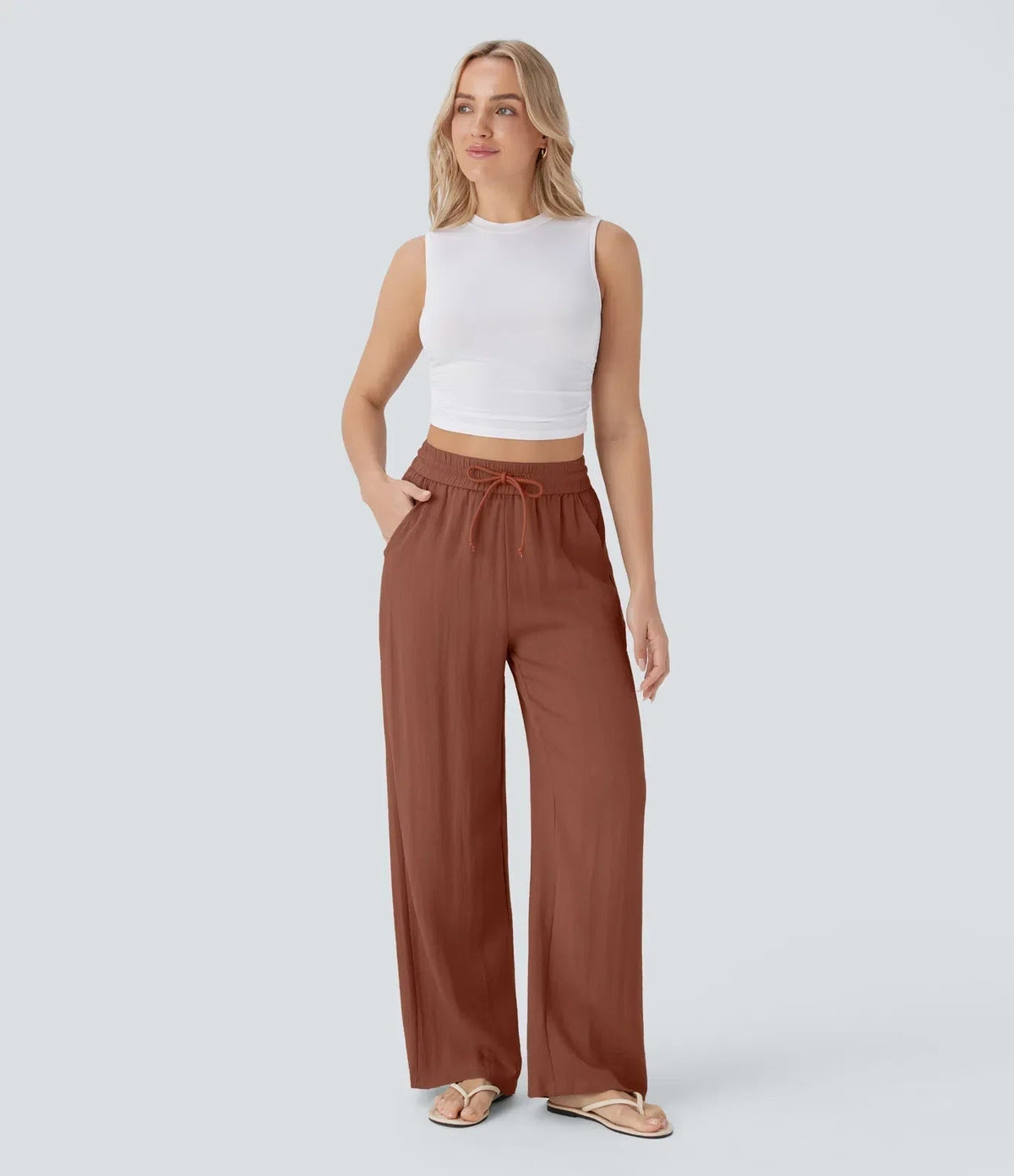 Rust brown wide-leg trousers with elastic waistband and drawstring, relaxed drape.