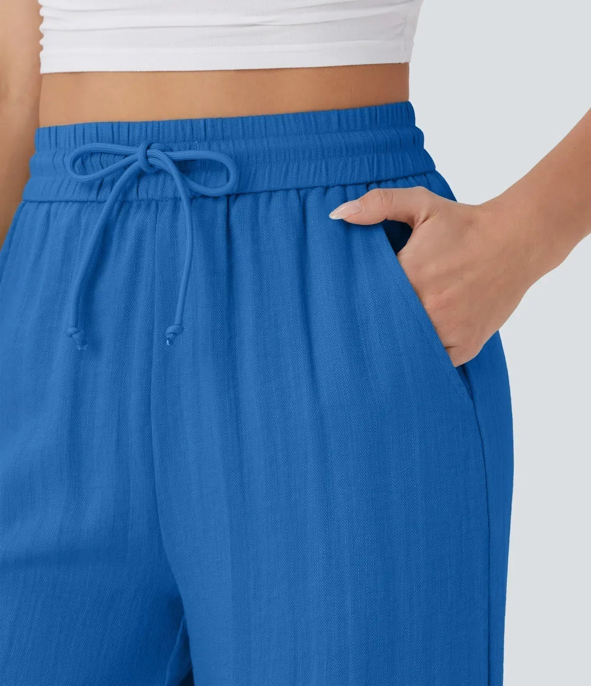 Close-up of blue drawstring waist on wide-leg trousers with elastic waistband.