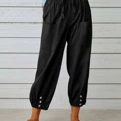 Black relaxed-fit trousers with elastic waist, drawstring, side pockets, button cuff hem.