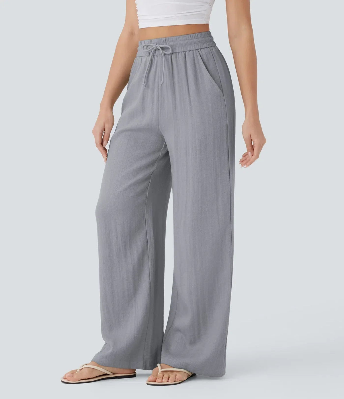 Grey wide-leg trousers with elastic waistband and drawstring, loose flowing fit.