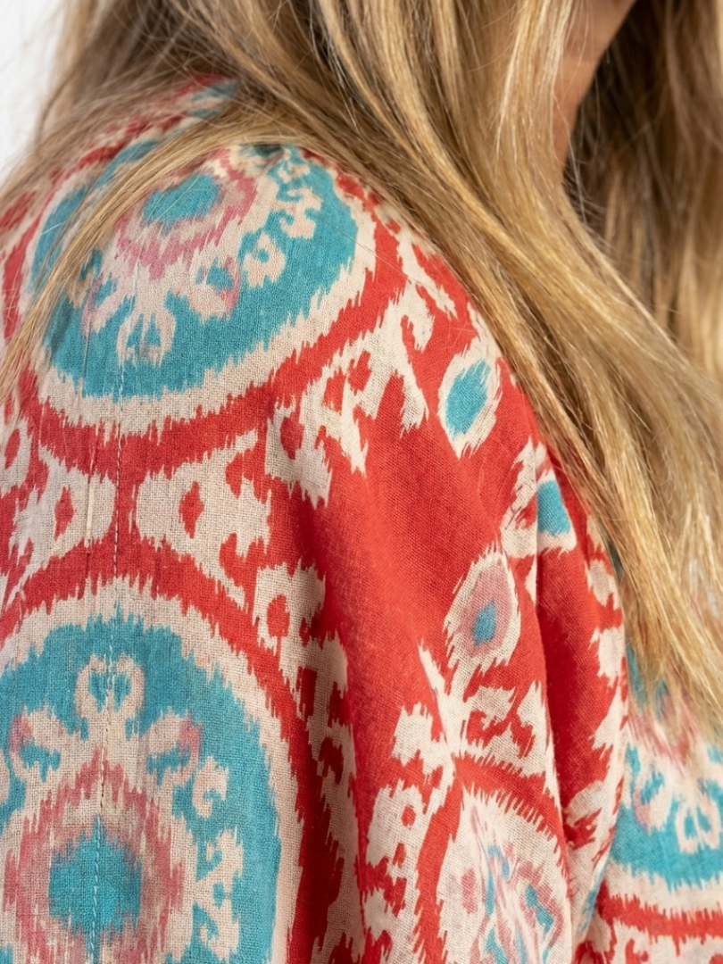 Red paisley print dress fabric detail with teal and white, short-sleeve V-neck