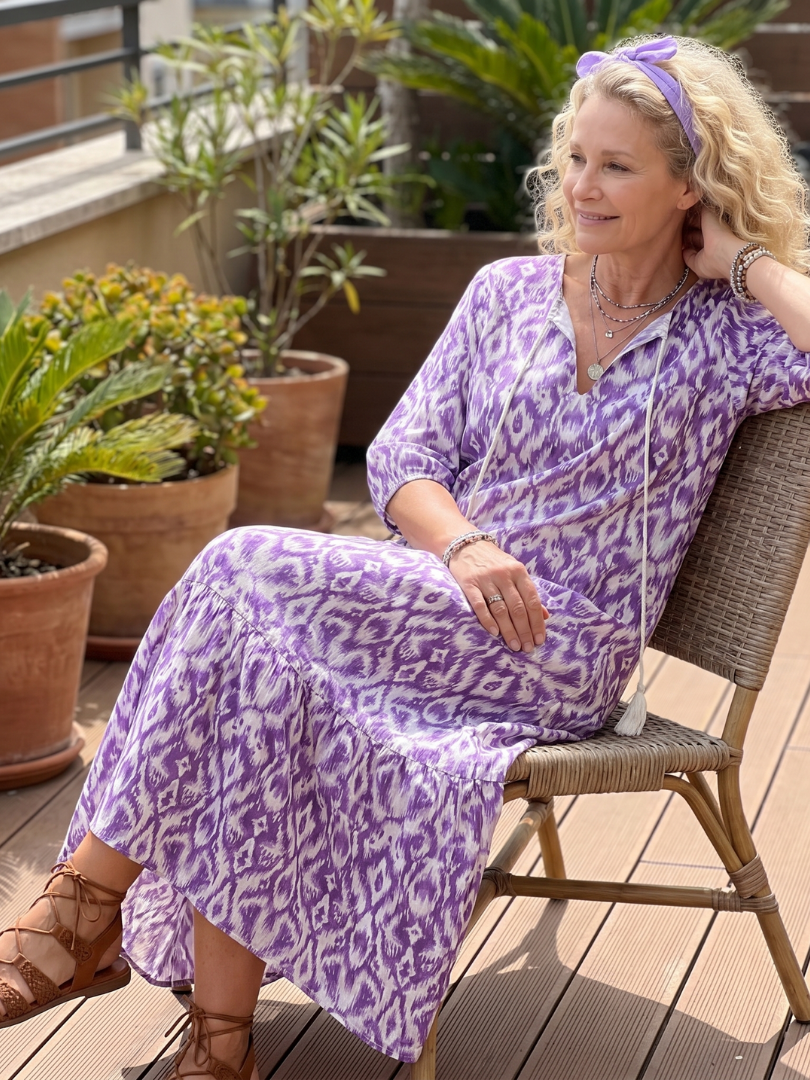 Purple printed midi dress with tie-neck, short sleeves, tiered skirt, seated