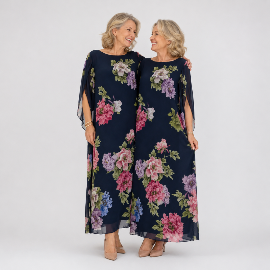 Floral maxi dress in dark blue with pink and lavender blooms, sheer cape sleeves