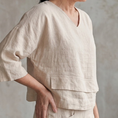 Beige layered V-neck top with tiered hem detail, matching wide-leg pants