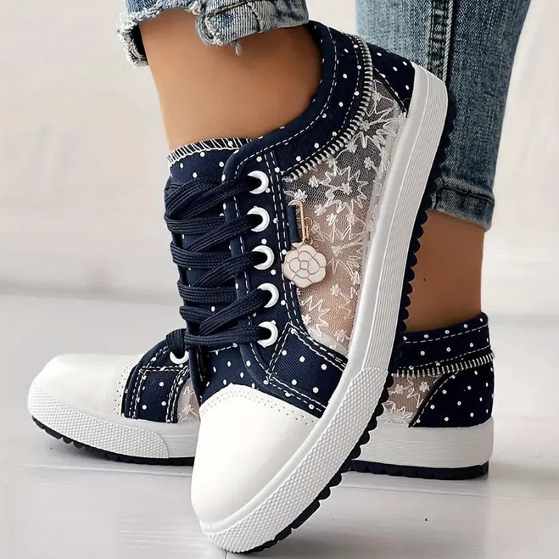 Navy canvas floral sneakers with white polka dots, lace-up front, textured side sole.