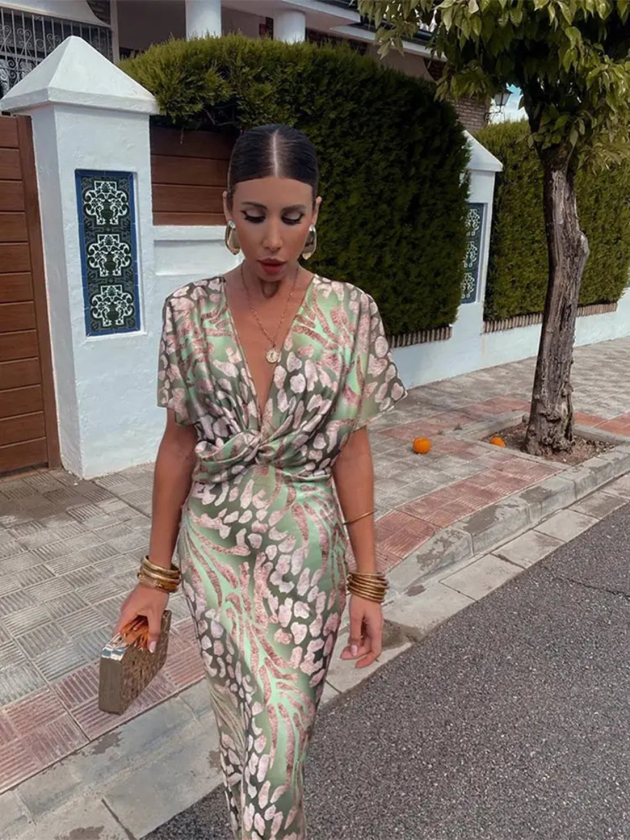 Printed green midi dress with V-neck, twist-front knot, and short puff sleeves.