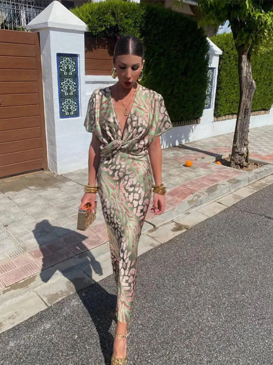 Printed green V-neck midi dress with twist-front knot and short puff sleeves.