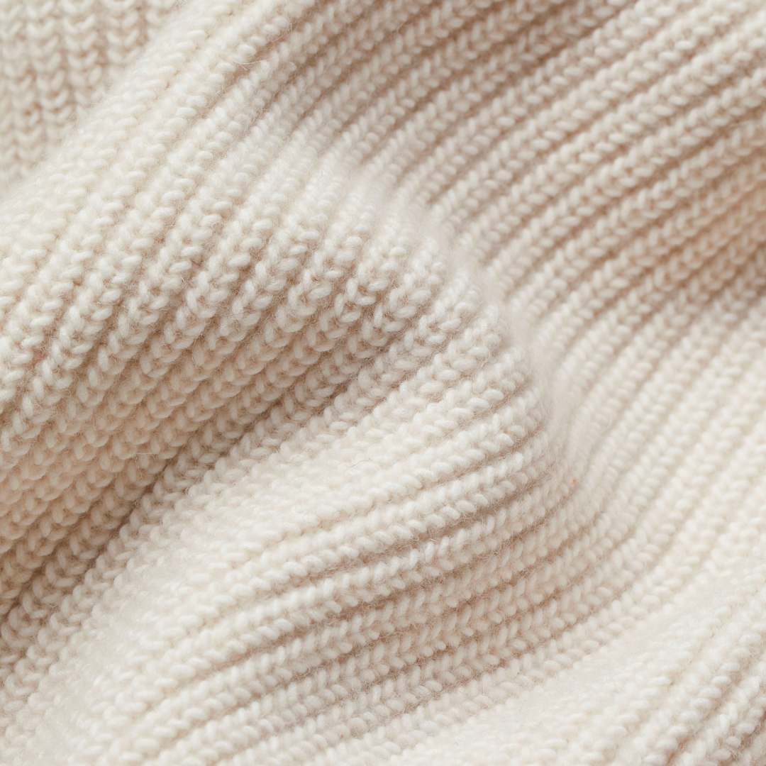 Close-up of cream chunky ribbed knit fabric with textured weave