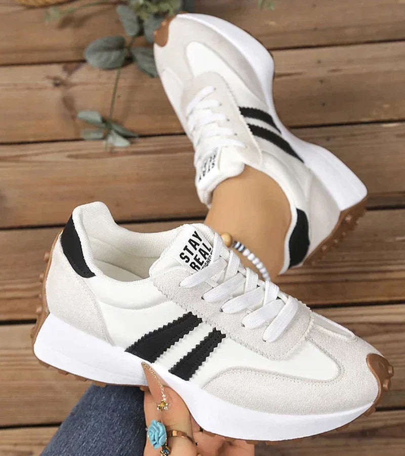 White and light gray lace-up trainers with black side stripe detail and thick sole