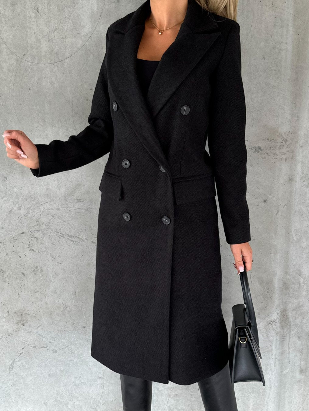 Black longline double-breasted coat with notched lapels and flap pockets