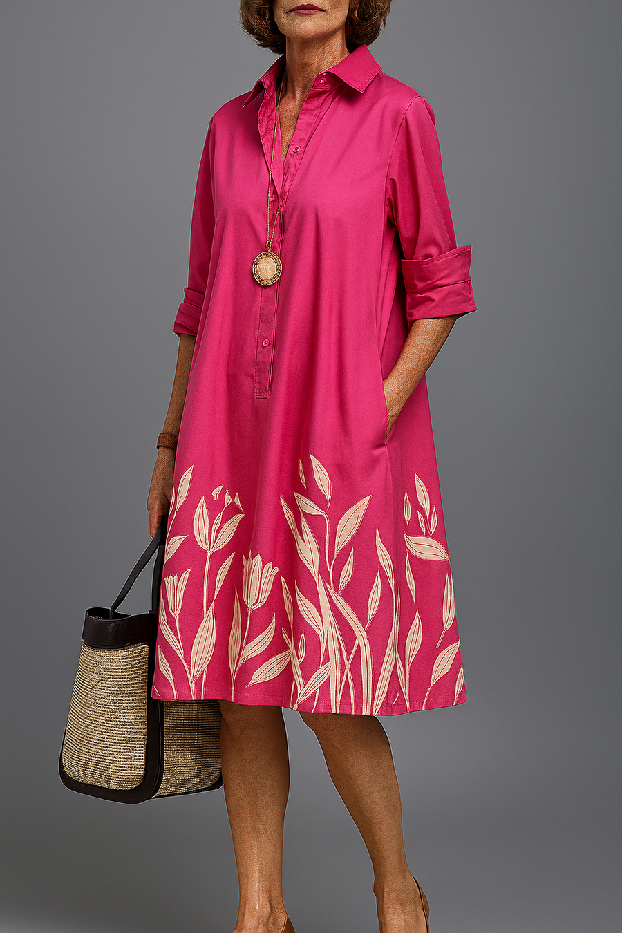 Pink button-front midi dress with collar, roll-tab sleeves, and leaf print hem.
