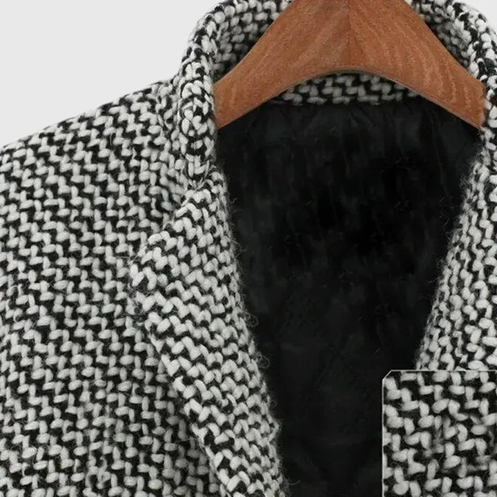 Gray-and-black herringbone coat close-up with black inner lining and wooden hanger